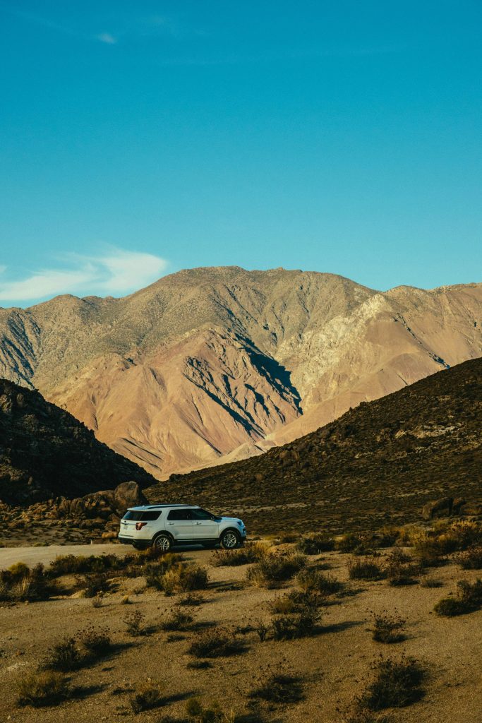 SUV traversing a rugged mountain landscape under a clear blue sky, showcasing adventure and nature.